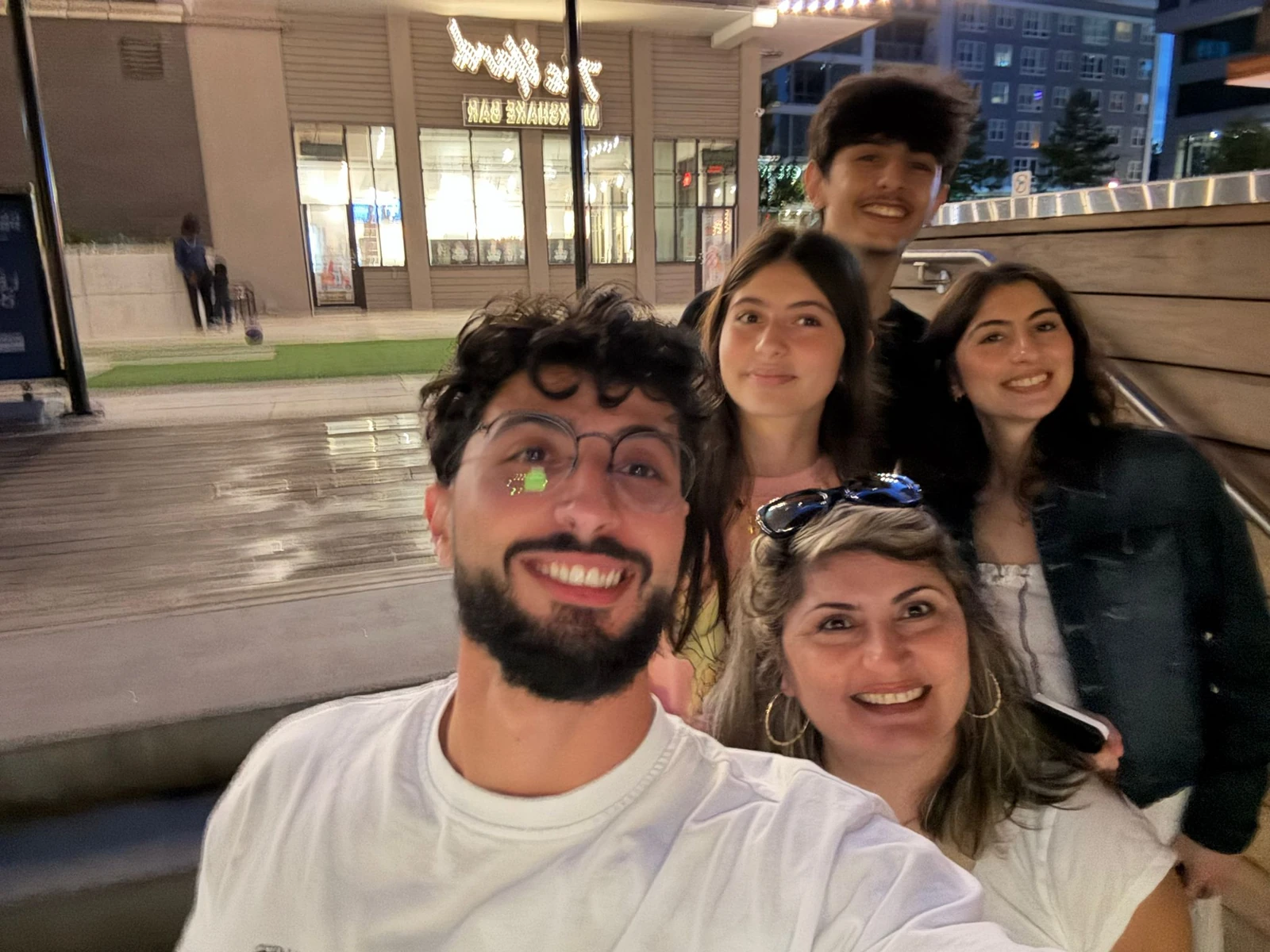 Five people taking an evening selfie outside.