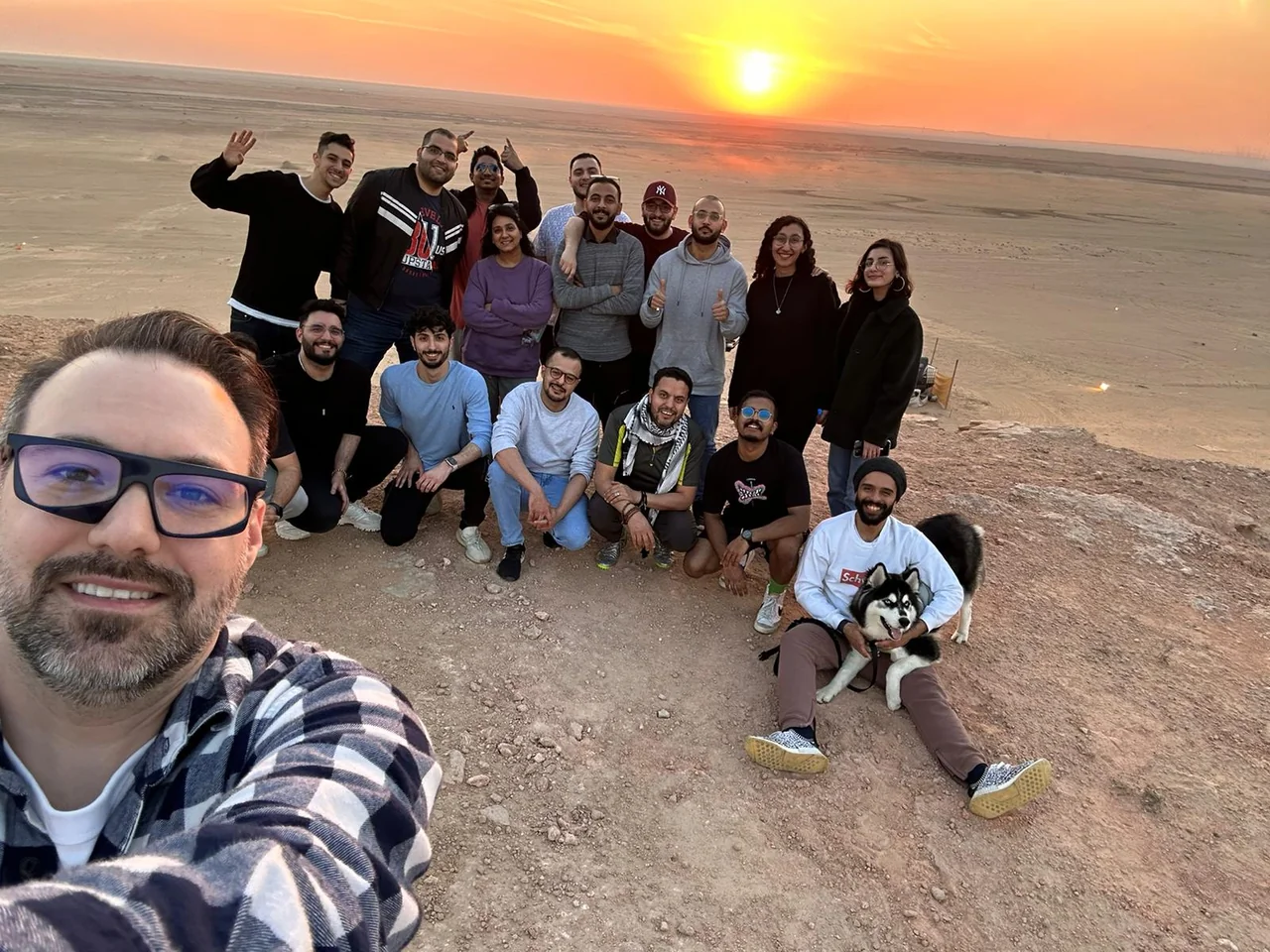 A group of friends posing together in the desert at sunset.